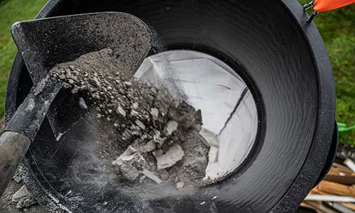 Bauschutt mit Schaufel in Schuttrutsche schütten – flexible Bauschuttrutsche im Einsatz